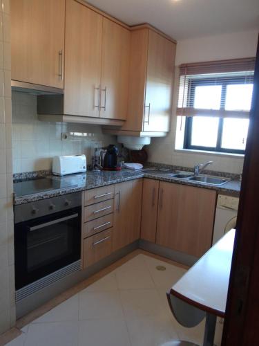 a kitchen with wooden cabinets and a stove top oven at Porto Marina @Vilamoura in Vilamoura