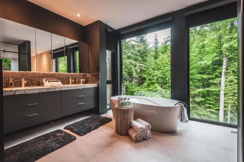 uma casa de banho com banheira e uma grande janela em Luxurious Heaven Lodge Tremblant-4 Bdrs W Hottub em Mont-Tremblant