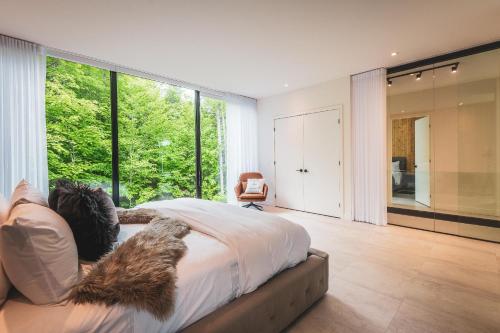 um quarto com uma cama e uma grande janela em Luxurious Heaven Lodge Tremblant-4 Bdrs W Hottub em Mont-Tremblant