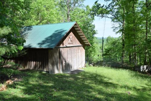a brown barn with a green roof in a field at Mountain Shade in Townsend