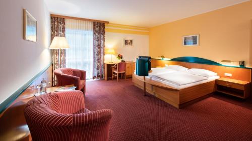 ein Hotelzimmer mit einem Bett und zwei Stühlen in der Unterkunft Parkhotel zur Klause in Bad Hall