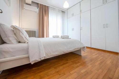 una camera bianca con un letto bianco e un pavimento in legno di Διαμέρισμα 55 τ.μ. στο κέντρο με δωρεάν πάρκινγκ a Larisa