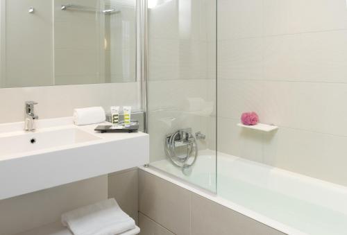 a white bathroom with a shower and a sink at Mercure Paris Levallois in Levallois-Perret