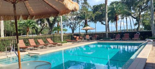 una piscina con sillas y sombrilla en Tropical Marina & Resort on Lake Beresford, en De Land