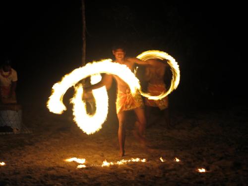 a man is standing in the dirt with fire at Serenity Beaches Resort in Uoleva Island