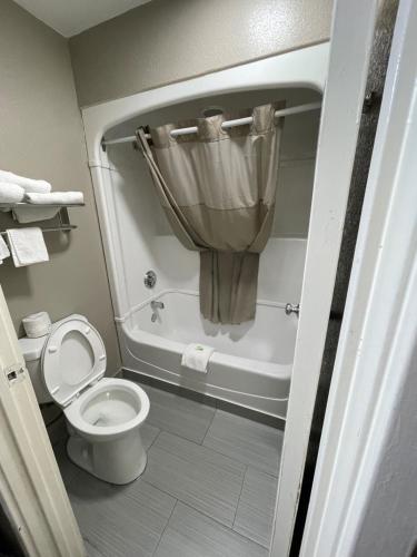a bathroom with a toilet and a tub with a curtain at Super 7 Inn in Memphis