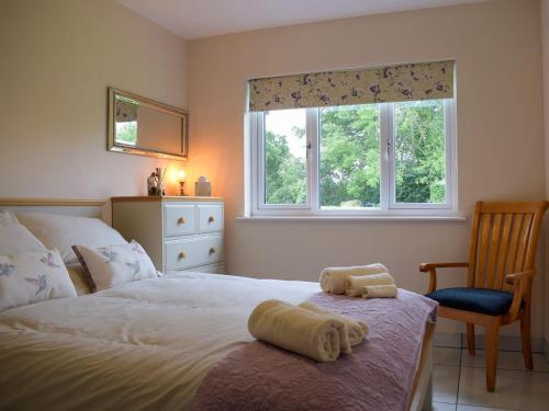 a bedroom with a bed and a chair and a window at Bumble Lodge in Llynclys