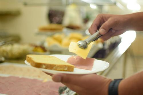 a person holding a plate with a piece of cheese and bread at Hotel Nacional Inn Foz do Iguaçu in Foz do Iguaçu