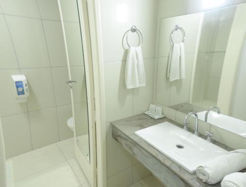 a white bathroom with a sink and a shower at Hotel Nacional Inn Foz do Iguaçu in Foz do Iguaçu