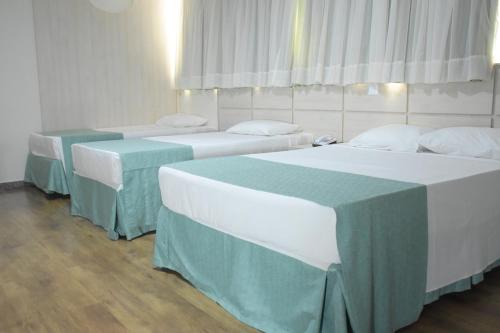 a room with three beds and two tables at Hotel Nacional Inn Foz do Iguaçu in Foz do Iguaçu