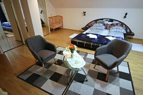 - un salon avec deux chaises et un lit dans l'établissement Beáta Apartman, à Gyula