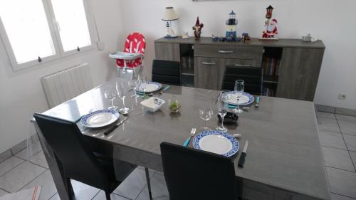 - une table à manger avec des assiettes et des verres à vin dans l'établissement Plaisir en baie, à Saint-Blimont