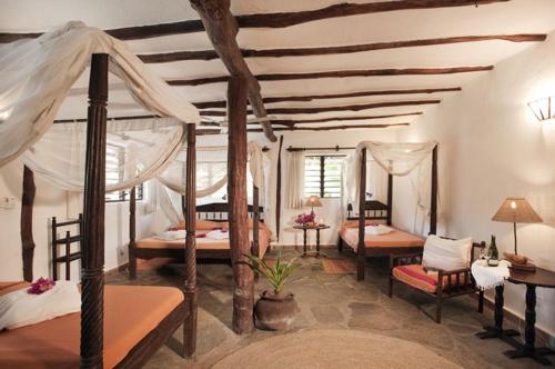 1 dormitorio con 4 camas y techo con vigas. en Diani Marine Divers Village, en Diani Beach