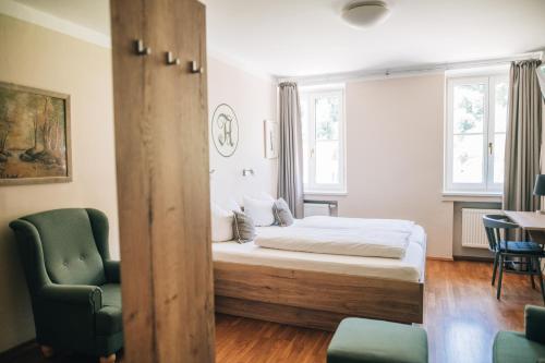 a bedroom with a bed and a green chair at Angermühle Landgasthof in Altenmarkt an der Alz