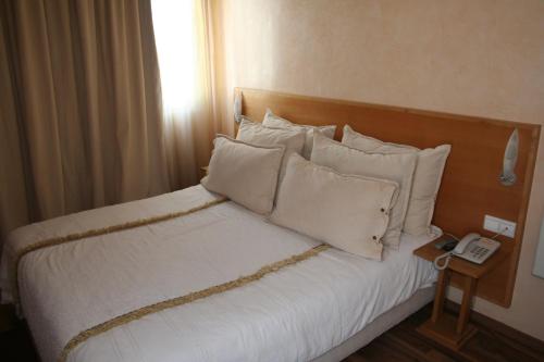 a bed with white pillows and a phone on a table at Casablanca Suites & Spa in Casablanca