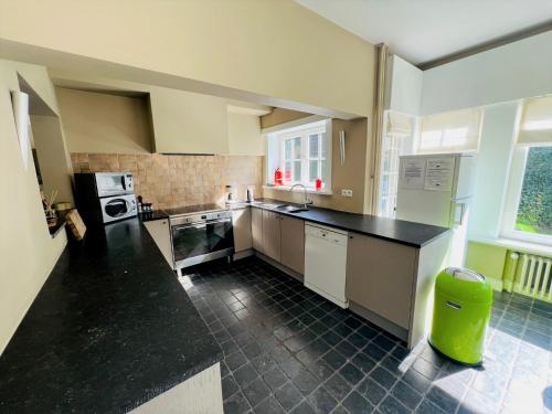a large kitchen with a black counter top at Le Coin Vert in Bruges
