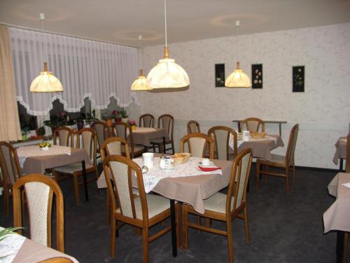 un comedor con mesas, sillas y luces en Pension Wölfel, en Bad Steben