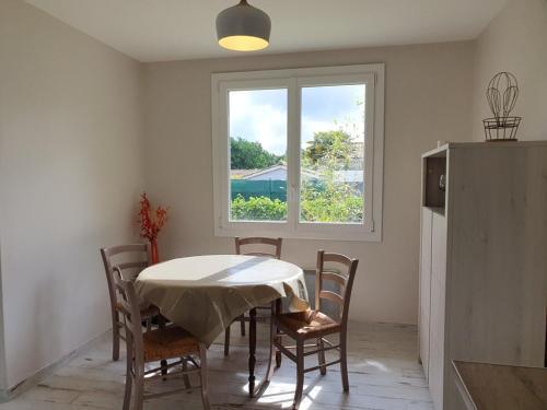 eine Küche mit einem Tisch und Stühlen sowie einem Fenster in der Unterkunft Charmant séjour à Andernos in Andernos-les-Bains