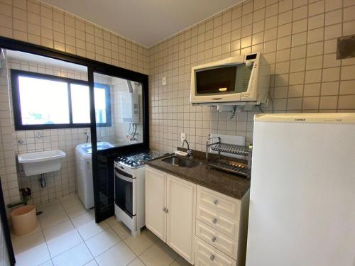 uma pequena cozinha com um lavatório e um micro-ondas em Flat Residence Moema c/ cozinha e lavadora UH104 em São Paulo