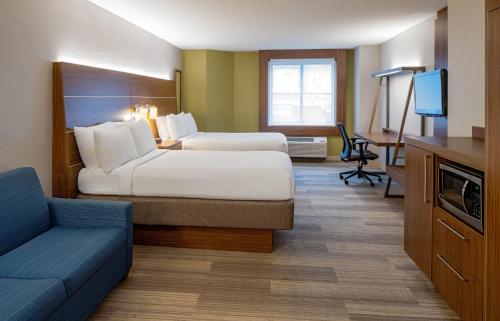 ニューオーリンズにあるホリデイイン エクスプレス ニューオーリンズ ダウンタウンのベッド2台とソファが備わるホテルルームです。