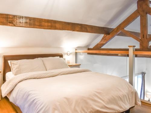 a bedroom with a large white bed with wooden beams at Swallow Barn in Hargrave