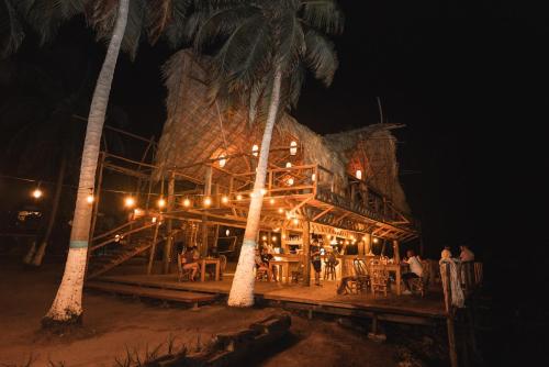 a restaurant on the beach at night with palm trees at La Playita Isla Fuerte in Puerto Limón