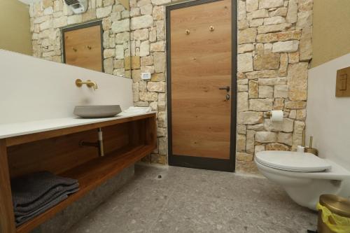 a bathroom with a sink and a toilet and a stone wall at Genesis Land Desert hospitality in Kfar Adumim