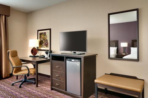 a hotel room with a desk and a tv and a room at Holiday Inn Express Hotel & Suites Billings by IHG in Billings