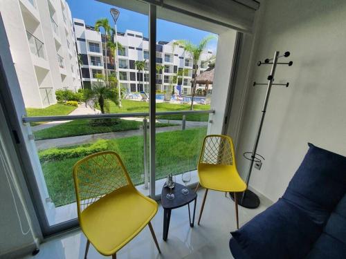 a room with two yellow chairs and a large window at Departamento de lujo en Manzanillo, planta baja frente a la alberca in Manzanillo