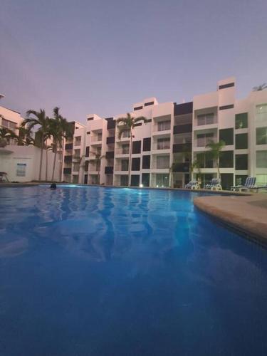 a large blue swimming pool in front of a building at Departamento de lujo en Manzanillo, planta baja frente a la alberca in Manzanillo
