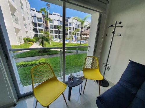 a room with two yellow chairs and a large window at Departamento de lujo en Manzanillo, planta baja frente a la alberca in Manzanillo