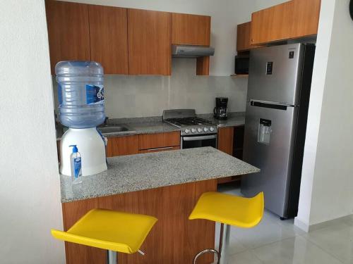 a kitchen with a blender and two yellow stools at Departamento de lujo en Manzanillo, planta baja frente a la alberca in Manzanillo