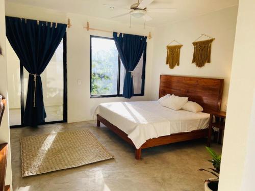 1 dormitorio con 1 cama grande y cortinas azules en Santuario Jungle, en Akumal