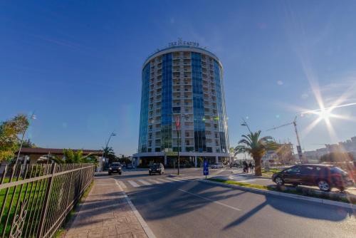 a tall building on a city street with cars on the road at Hotel Tre Canne in Budva