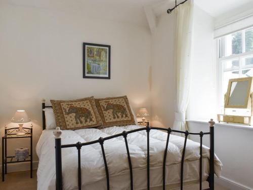 a bedroom with a bed with white sheets and a window at Primrose Cottage in Bowness-on-Windermere