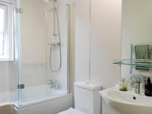 a white bathroom with a shower and a toilet and a sink at The Butchers Cottage in Edzell