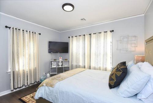 a bedroom with a bed and a flat screen tv at BLUE FLAMINGO'S CHARMING HOME-Heart of Tulsa2- Cherry St-Expo-11th in Tulsa