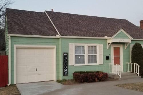 a green house with a white garage at BLUE FLAMINGO'S CHARMING HOME-Heart of Tulsa2- Cherry St-Expo-11th in Tulsa