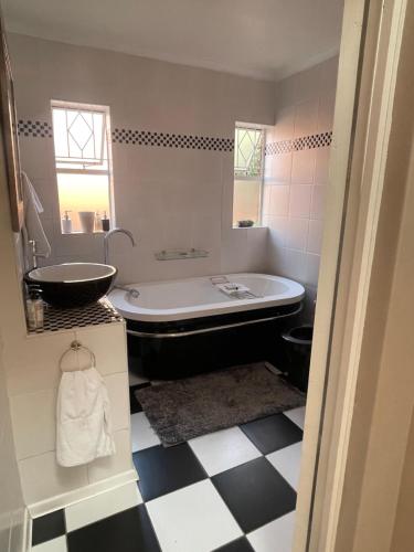 a bathroom with a bath tub and a sink at Tranquil Haven in Kempton Park