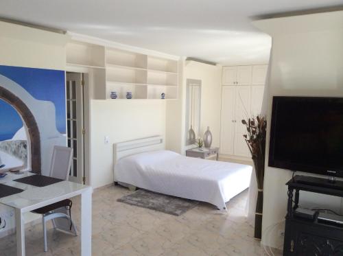 a bedroom with a bed and a desk and a tv at Penthouse Ventur in Caniço