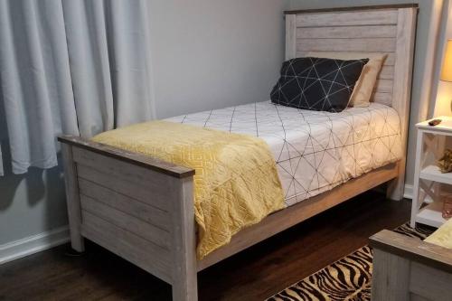 a bed with a wooden headboard with a yellow blanket at BLUE FLAMINGO'S CHARMING HOME-Heart of Tulsa2- Cherry St-Expo-11th in Tulsa