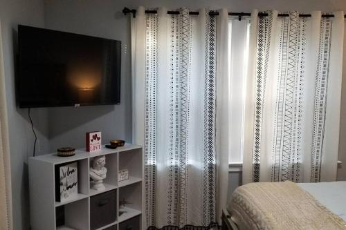 a bedroom with a bed and a television and curtains at BLUE FLAMINGO'S CHARMING HOME-Heart of Tulsa2- Cherry St-Expo-11th in Tulsa