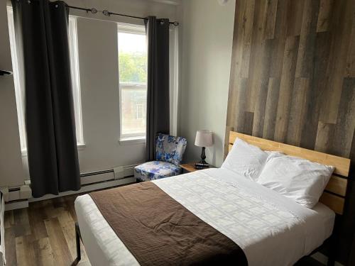 a bedroom with a bed and a window and a chair at Commercial Hotel in Edmonton