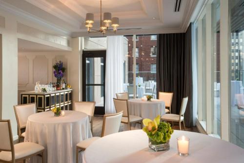 a restaurant with white tables and chairs and windows at Kimpton Hotel Monaco Pittsburgh, an IHG Hotel in Pittsburgh