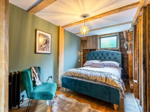 a bedroom with a blue bed and a chair at Old Shires Barn in Norton