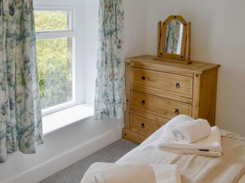 1 dormitorio con tocador, espejo y ventana en Thistle Cottage, en Glanton