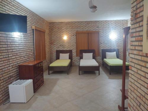 a room with two beds and a brick wall at Pousada Solar das Fontes in Beberibe