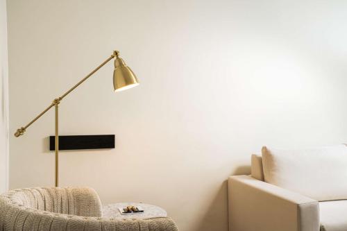 a white living room with a lamp and a chair at elaya hotel vienna city center in Vienna