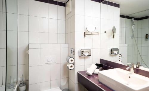 bagno bianco con lavandino e specchio di elaya hotel vienna city west a Vienna