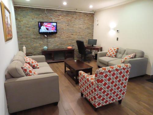 a living room with couches and a tv on a brick wall at St Charles Hotel Downtown Hudson in Hudson